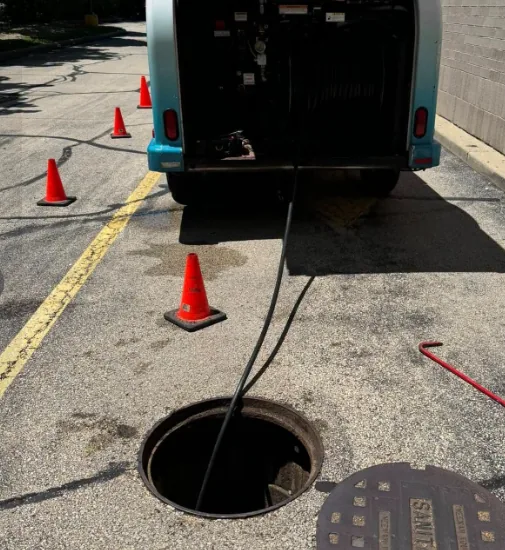 Drain cleaning truck with cable running into a sanitary sewer manhole