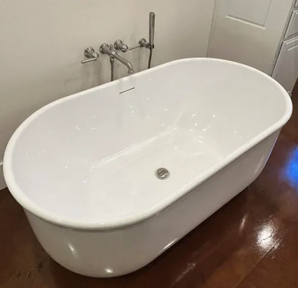 Freestanding white bathtub with a chrome drain