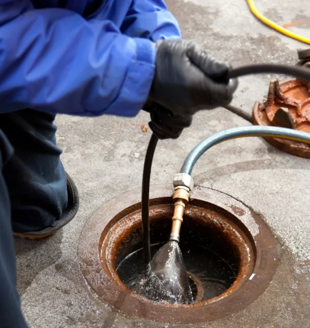 Hydro jetting nozzle blasting water down a drain opening