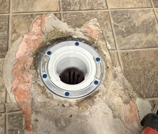 Exposed floor drain flange with new bolts set in a tile floor