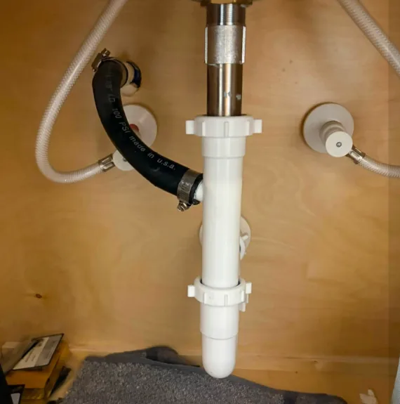 White PVC P-trap and drain pipes under a bathroom sink