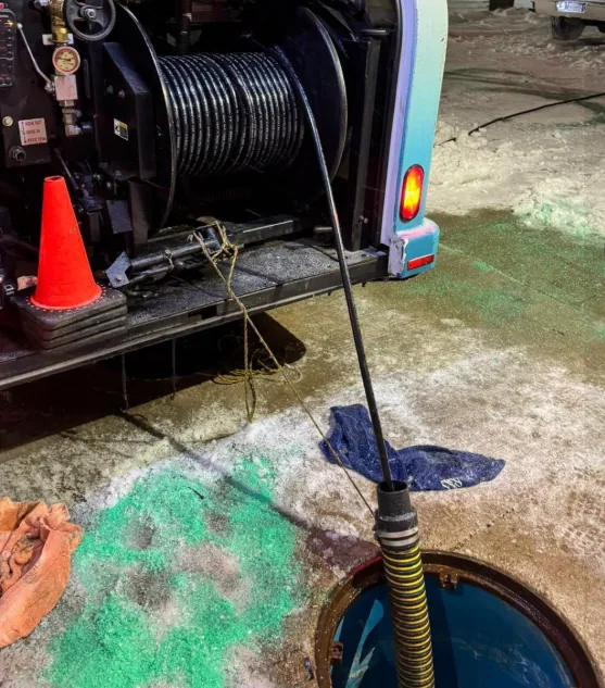 Drain cleaning truck working a sewer manhole in winter conditions